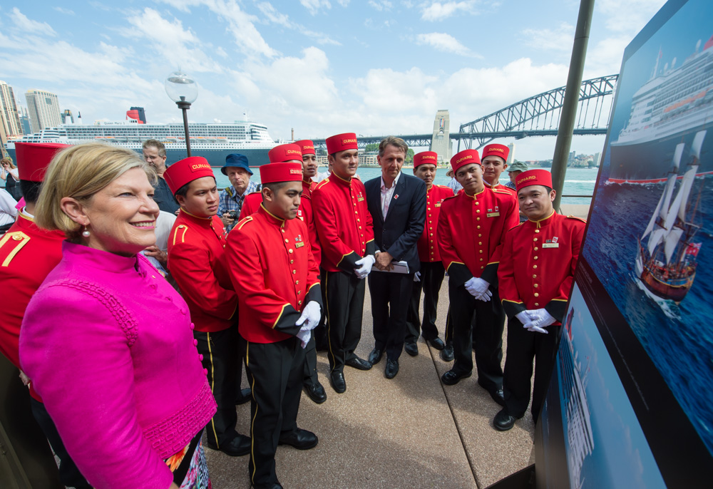 Carnival Australia CEO Ann Sherry photographer James Morgan and Queen Mary 2 bellboys  admire an image from the OneSevenFive exhibition